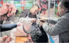  ??  ?? A butcher sells yak meat at a market in Beijing.