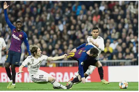  ??  ?? Getting shirty: Real Madrid’s Luka Modric taking an unusual route to stop Barcelona ace Lionel Messi. — AP