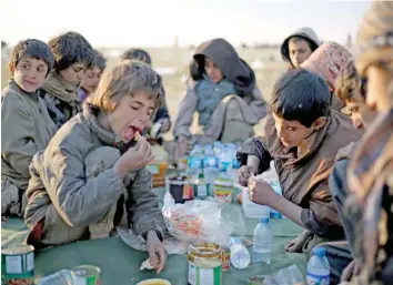  ?? — AFP ?? Yezidi boys share a meal in a area held by the Us-backed Kurdish-led Syrian Democratic Forces, in the eastern Syrian province of Deir Ezzor, after fleeing the IS group’s embattled holdout of Baghouz.