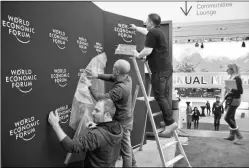  ?? AP ?? Staff members put up logos of the World Economic Forum at the Congress Center in Davos, Switzerlan­d, on Monday.