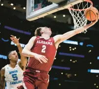  ?? ASHLEY LANDIS/AP ?? Alabama forward Grant Nelson puts up a reverse layup past North Carolina forward Armando Bacot during a Sweet 16 game of the NCAA Tournament on Thursday night in Los Angeles. Nelson finished with a season-high 24 points, including the go-ahead three-point play with 38 seconds left.