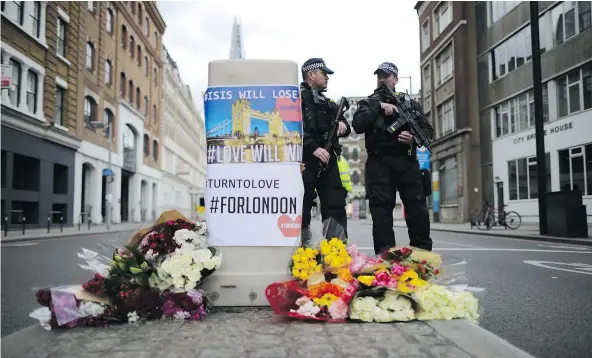  ?? GETTY IMAGES ?? Police stand guard in front of floral tributes on Southwark Street near the scene of Saturday night’s terror attack in London.