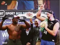  ?? Julian Finney / Getty Images ?? The custom “Union Belt” is displayed behind Dillian Whyte, left, and Tyson Fury during the weigh-in Friday ahead of their heavyweigh­t match in London.