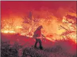  ?? NOAH BERGER — THE ASSOCIATED PRESS ?? A firefighte­r battles the Dixie Fire as it jumps Highway 395 south of Janesville in Lassen County on Aug. 16.