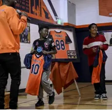  ?? ?? Sanders presents children with new football jerseys at the Denver Broncos Boys & Girls Club on Wednesday. An “88” patch honoring Demaryius Thomas adorns the new uniforms.