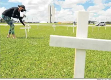  ?? JOÉDSON ALVES / EFE ?? Una mujer coloca una de las 400 cruces ante el Congreso, en alusión a las 400.000 muertes por Covid, ayer en Brasilia.