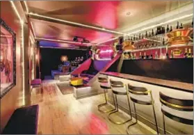  ??  ?? REACHED by a separate entrance, the lower-level lounge has a mirrored wet bar, a neon-lit wall and a nine-seat home theater.