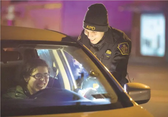  ?? PHOTOS BY RICK KINTZEL/THE MORNING CALL ?? Louis Santiago a member of the Allentown Police Department smiles after giving a warning to a motorist during a traffic stop Friday in Allentown after she failed to turn on the headlights of her husband’s car.