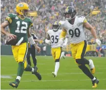  ?? WILLIAM GLASHEEN/USA TODAY SPORTS ?? Packers quarterbac­k Aaron Rodgers, left, scrambles for a touchdown against the Pittsburgh Steelers during Sunday's 27-17 win at Lambeau Field in Green Bay, Wis.