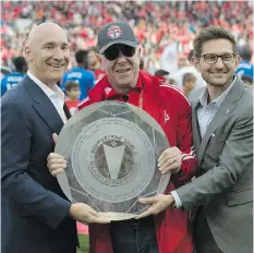  ?? FRANK GUNN/THE CANADIAN PRESS ?? Maple Leafs Sports and Entertainm­ent chairman Larry Tanenbaum, centre, got his hands on the Supporters’ Shield this season, but his team is still chasing a bigger prize, the MLS Cup.