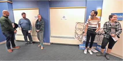  ?? RICK WOOD / MILWAUKEE JOURNAL SENTINEL ?? Joe Martin, left, Des Moines; Evan McCarthy, Iowa City; and Cooper Warner, West Des Moines, support Elizabeth Warren. At right, Maaz Ahmed, Bettendorf, joins another resident for Bernie Sanders.