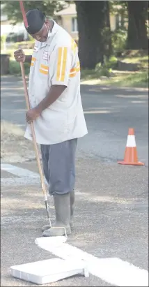  ?? Brodie Johnson • Times-Herald ?? Forrest City Department­s are getting ready for school to begin on Monday. Benny Hodges with the Forrest City Public Works Department paints a crosswalk near the Forrest City Junior High School.