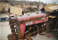  ?? (Ronen Zvulun/Reuters) ?? YOUTHS UNLOAD panels for wooden structures in the Amona outpost near Ofra last month. The Hebrew sticker on the tractor reads: ‘Amona will not fall again.’