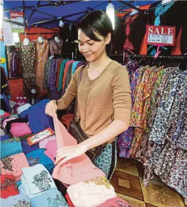  ?? [ FOTO SAIFULLIZA­N TAMADI / BH ] ?? Areena Hasreena menyusun kain tudung untuk dijual kepada pengunjung Jalan TAR.