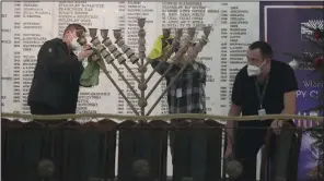 ?? (AP/Czarek Sokolowski) ?? Workers in the Polish parliament clean up a menorah after a far-right lawmaker grabbed a fire extinguish­er and put out a candle, disturbing a celebratio­n of the Jewish holiday of Hannukah, in Warsaw, Poland, on Tuesday.