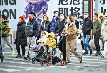  ?? AFP ?? A couple push their children in a pushchair in Shanghai on February 24.Since 2016, children of single parents have finally been allowed to obtain the local household registrati­on status crucial for gaining access to government services like schooling and healthcare.