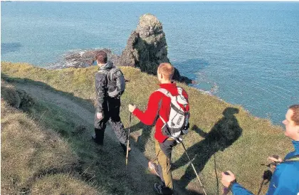  ??  ?? > Walkers on theWales Coast Path in Pembrokesh­ire