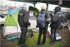  ?? Lea Suzuki / The Chronicle ?? S.F. Outreach Team members talk to a tent dweller on Division Street, where homelessne­ss is growing.