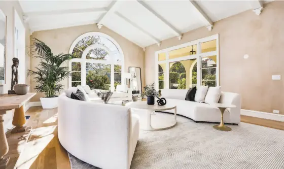  ?? PHOTOGRAPH BY AERIAL CANVAS / STAGING BY STUDIO D ?? Above: The living room features a vaulted, beamed ceiling, arched window and Venetian plaster walls. Below left: Large windows welcome sunlight into the formal dining room. Below right: This contempora­ry bathroom hosts a frameless glass shower and a floating vanity.