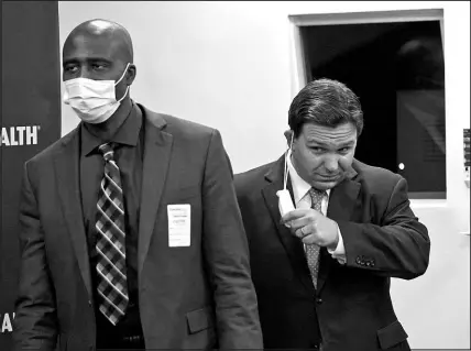  ?? WILFREDO LEE / ASSOCIATED PRESS FILE (2022) ?? Florida Gov. Ron Desantis, right, takes off his mask, worn to help prevent the spread of COVID-19, as he arrives at a news conference Jan. 3, 2022, with Florida Surgeon General Dr. Joseph Ladapo at Broward Health Medical Center in Fort Lauderdale, Fla.