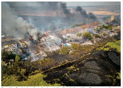  ?? ?? Grey skies: Smoke rises above the devastatio­n that shattered the village community