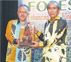  ??  ?? Sapuan (left) presents a memento to Len Talif. — Photo by Muhammad Rais Sanusi