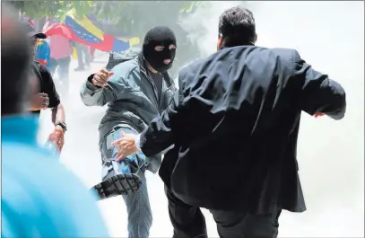  ?? Fernando Llano ?? The Associated Press A masked man kicks at opposition lawmaker Franco Casella in a melee Wednesday during a special National Assembly session coinciding with Venezuela’s independen­ce day.