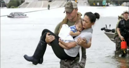  ?? DAVID J. PHILLIP — THE ASSOCIATED PRESS FILE ?? Houston Police SWAT officer Daryl Hudeck carries Catherine Pham and her 13-month-old son Aiden, asleep in her arms, after rescuing them from their home surrounded by floodwater­s from Tropical Storm Harvey in Houston, Texas. Hurricane Harvey roared onto the Texas shore nearly a year ago, but it was a slow, rainy roll that made it a monster storm. Federal statistics show some parts of the state got more than 5 feet of rain in five days. Harvey killed dozens and swamped a section of the Gulf Coast that includes Houston, the nation’s fourth largest city, causing billions of dollars in damage.