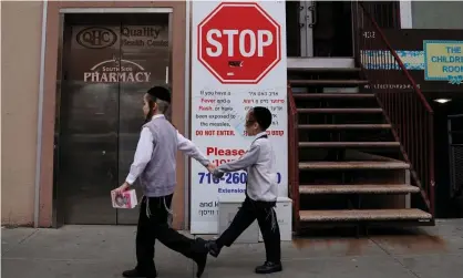  ?? Photograph: Carlo Allegri/Reuters ?? Children walk past a sign about a measles outbreak Brooklyn, New York, on 25 April.