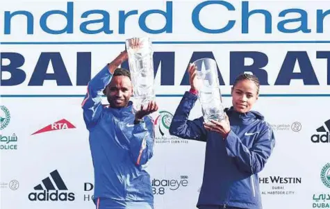  ?? Ahmed Ramzan/ Gulf News ?? Winners Mosinet Geremew of Ethiopia and Roza Dereje pose with their trophies after winning the Standard Chartered Dubai Marathon 2018 in Dubai yesterday.