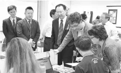  ??  ?? Raymond (standing second right) observing one of the activities conducted in the Institut Sinaran's new language laboratory together with Fong (standing third right) and Marie (standing right).