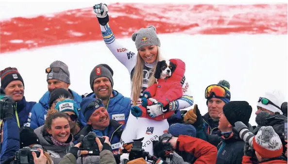  ?? FOTO: RTR ?? Hoch soll sie leben: Freunde und Betreuer feiern mit Lindsey Vonn die Bronzemeda­ille. Hündchen Lucy hat es schön warm im Schneeanzu­g.