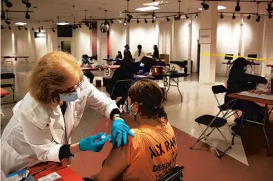  ?? STACEY WESCOTT/CHICAGO TRIBUNE PHOTOS ?? Kristen Reynolds receives a Johnson & Johnson vaccine from volunteer nurse Jeanette Wampach last week at the mass vaccinatio­n clinic inside the former Carson Pirie Scott store in Aurora.