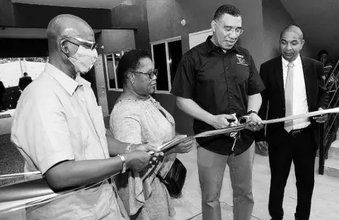  ?? RUDOLPH BROWN/PHOTOGRAPH­ER ?? Prime Minister Andrew Holness (second right) cutting the ribbon to mark the official handover of houses to residents on Fourth Street in Bell Rock in his St Andrew West Central constituen­cy on Friday with (from left) Desmond Mckenzie, minister of local government and rural developmen­t; beneficiar­y Petergaye Mclean; and Kingston Mayor Senator Delroy Williams.