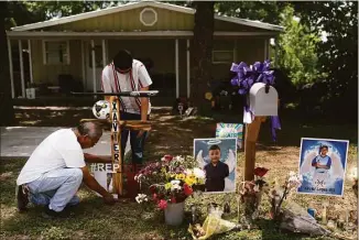  ?? Jae C. Hong / Associated Press ?? Jose Mata, top, a brother of Xavier Lopez, and a man, who declined to give his name, place a wooden cross decorated with a baseball bat at a memorial honoring his brother outside his home in Uvalde, Texas, on Tuesday. Lopez was one of the students killed in last week's shooting at Robb Elementary School.