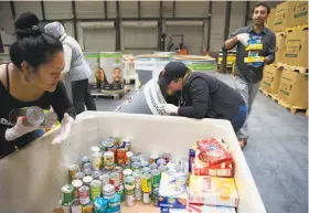  ??  ?? Joy Wi (left), Liz Drummond and Shawn Kann organize donations of food from collection barrels that have been placed at markets.