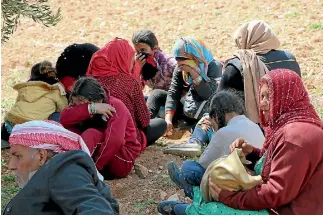  ?? PHOTO: AP ?? Syrians fleeing fighting between Turkish troops and Syrian Kurdish militia rest in a field between Afrin and Azaz in northweste­rn Syria.