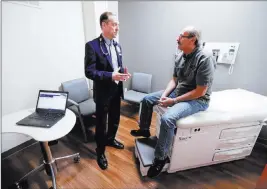  ?? Michael Conroy ?? The Associated Press Dr. John Lynch meets with patient Jeff Thieke during his visit to the Fiat Chrysler Automotive Clinic in Anderson, Ind.