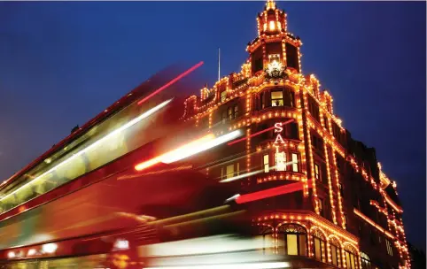  ?? (Luke MacGregor/Reuters) ?? A BUS CASTS light trails as it passes iconic department store Harrods in London. Qatar is one of the most high-profile investors in London, owning landmarks such as the Shard skyscraper, Harrods and Olympic Village, as well as luxury hotels. It also...