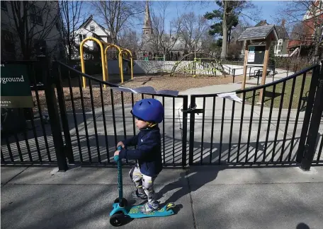  ?? NANCY LANE / HERALD STAFF ?? NO PLAYGROUND TODAY: A child scoots past the Billy Ward Playground, which was locked up after the town of Brookline closed playground­s due to the threat of the coronaviru­s on Monday.