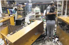  ?? Charles Rex Arbogast / Associated Press ?? Yogi Dalal hugs his daughter, Jigisha, in their food and liquor store that was vandalized in Chicago. Hundreds participat­ed in the spree, police said.