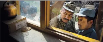  ?? (File Photo/AP/Anja Niedringha­us) ?? An Afghan soldier (left) and a police officer peek through a window April 1, 2014, as they queue with others to get their registrati­on card on the last day of voter registrati­on for presidenti­al elections outside a school in Kabul, Afghanista­n.