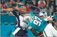  ?? MIKE EHRMANN / GETTY IMAGES / AFP ?? Jordan Phillips of the Miami Dolphins tries to thwart a pass by Tom Brady of the New England Patriots in the fourth quarter of Monday’s NFL game at Hard Rock Stadium in Miami Gardens, Florida. The Dolphins won 27-20.