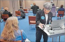  ?? SEAN D. ELLIOT/THE DAY ?? Liliana Fulchiero, right, helps Marge Lees of Simsbury schedule her second shot after getting her first dose of the Pfizer/BioNTech COVID-19 vaccine Friday during a clinic at Mohegan Sun.