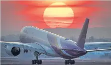  ?? Michael Probst, The Associated Press ?? An airbus A350 from Thai Airways lands at the airport in Frankfurt, Germany, as the sun sets on March 17.