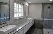  ?? ?? The redesigned primary bathroom includes a 12-foot, wall-mounted vanity with granite counter and walk-in shower with ceramic-tile surround.