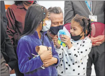  ?? Lea Suzuki The Associated Press ?? California Gov. Gavin Newsom takes a photo Monday with two children who both received their COVID-19 vaccines at the clinic at Unidos en Salud in San Francisco.