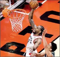  ?? AP/The Canadian Press/FRANK GUNN ?? Toronto Raptors forward Kawhi Leonard scores past Milwaukee Bucks guard Malcolm Brogdon during the second overtime of Game 3 of the NBA Eastern Conference finals Sunday in Toronto. Leonard had 36 points, 9 rebounds and 5 assists to help the Raptors win 118-112.