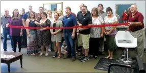  ?? Photo by Susan Holland ?? Hilarie Dodd, owner of the new Thairapy Hair Salon in Gravette, prepares to cut the ribbon at her shop June 6. She was joined at the ribbon-cutting by Gravette Mayor Kurt Maddox, city finance director Carl Rabey and several members of the Greater Gravette Chamber of Commerce.