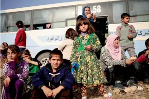  ?? Families who fled the fighting between Daesh and the Iraqi army sit beside a bus at a Peshmerga checkpoint in Iraq. — Reuters ??